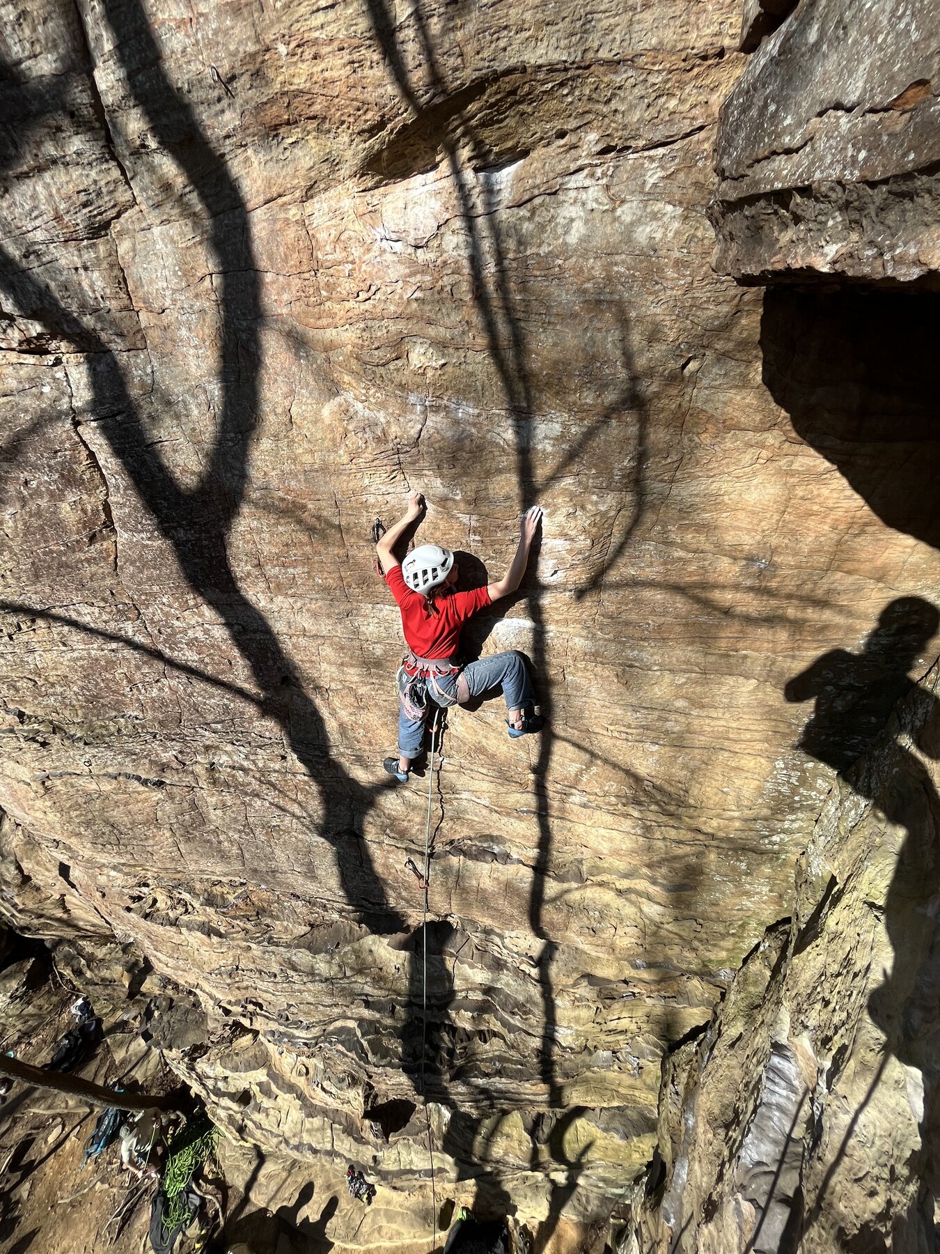Climber reaching past an overhanging cave feature on steep Corbin sandstone in the Daniel Boone National Forest, Red River Gorge